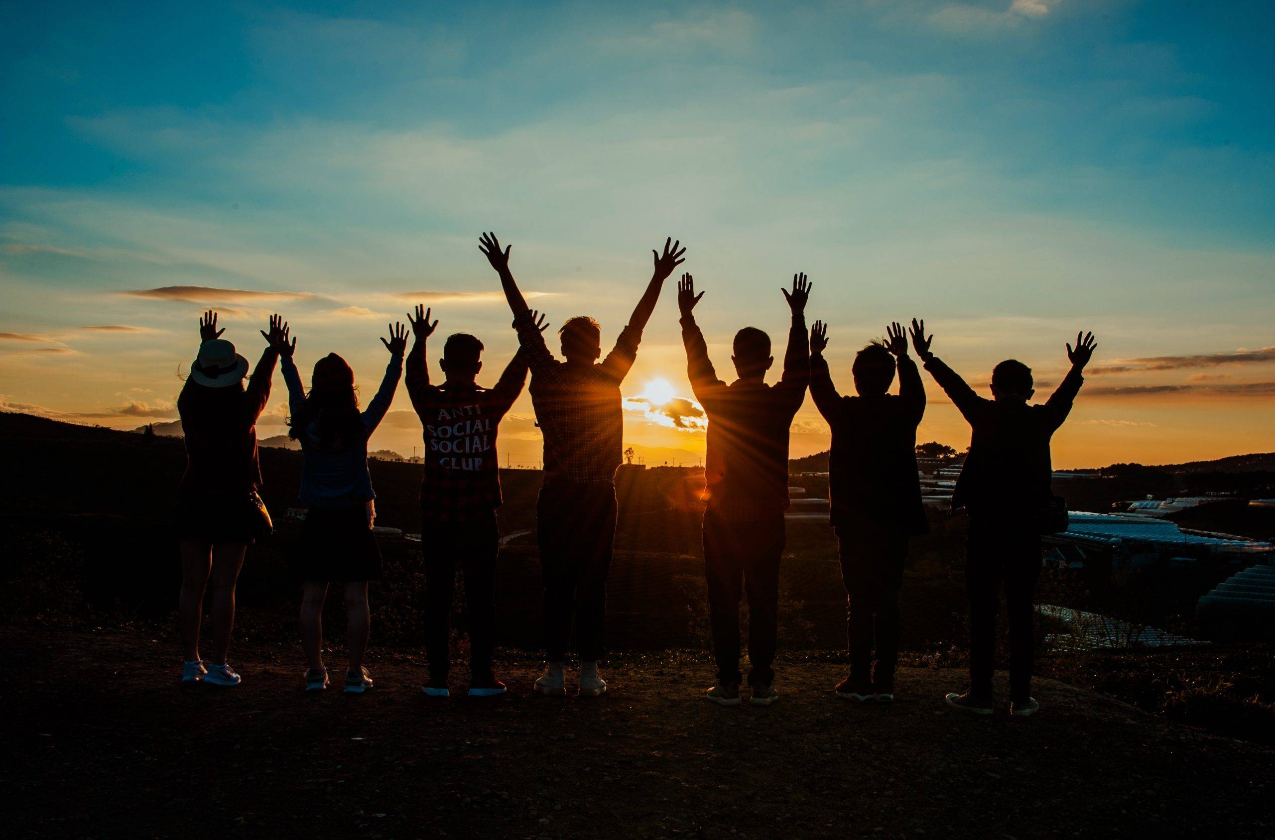 People looking at sunset with hands up